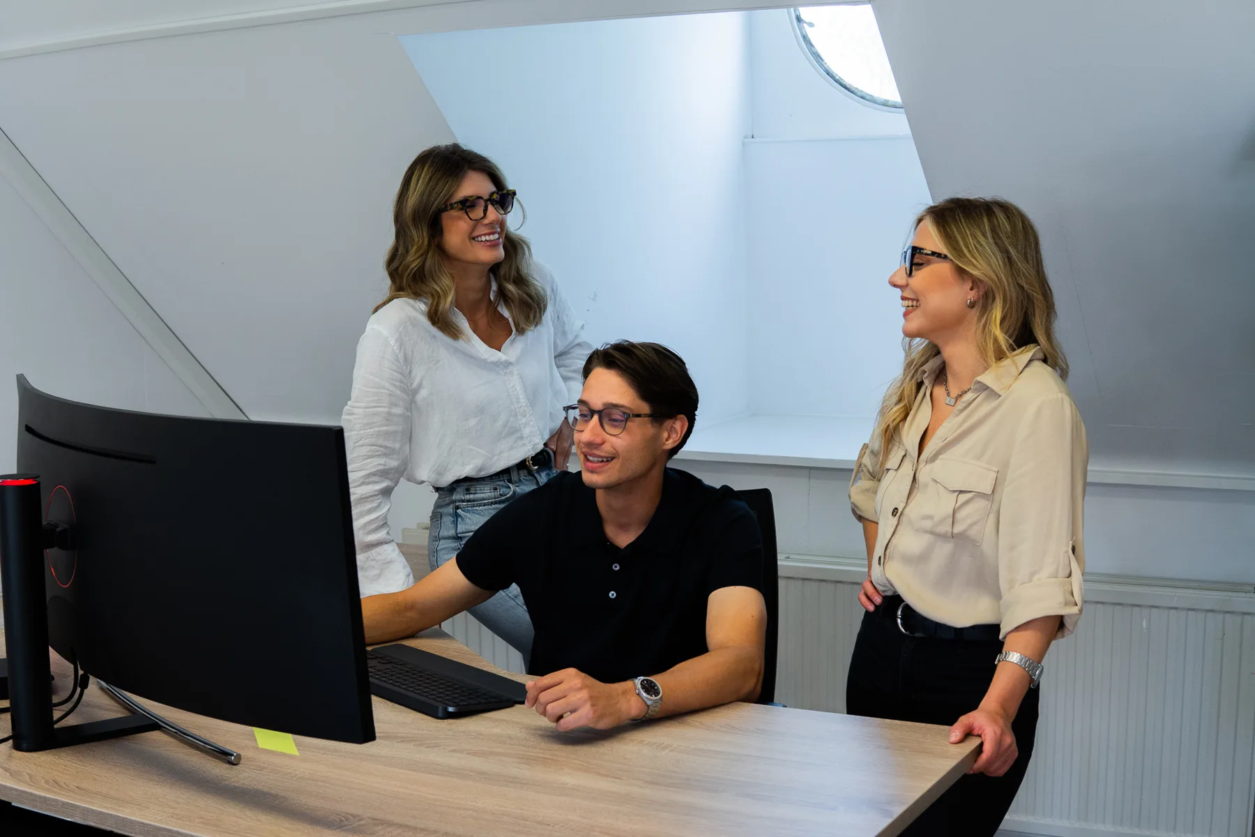 Drie collega’s van React2u kijken samen naar een scherm op kantoor